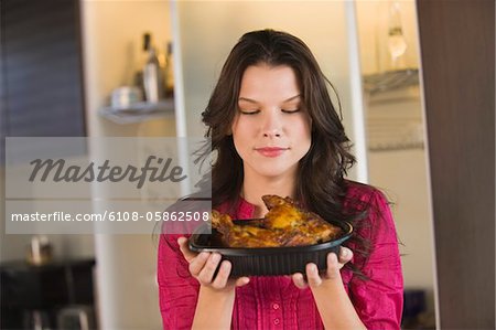 Woman holding a tray of roasted chicken