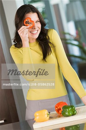 Femme regardant à travers un morceau de poivron rouge
