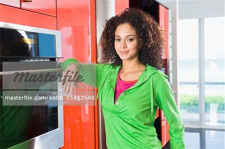 Woman leaning against an oven in the kitchen