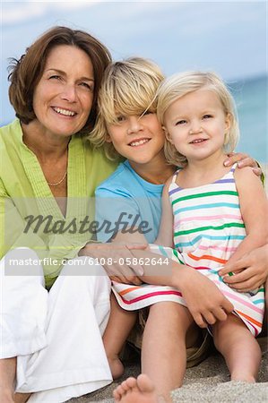 Frau sitzt mit ihren Enkeln am Strand