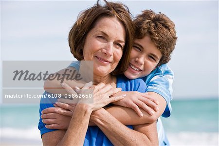 Boy hugging his grandmother on the beach