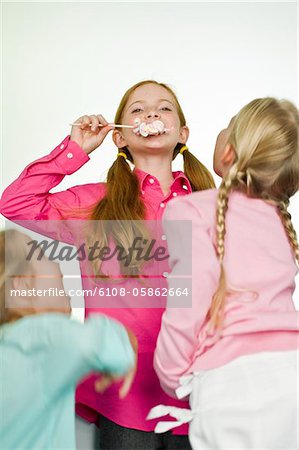 Girl eating a lollipop and her friends looking at her