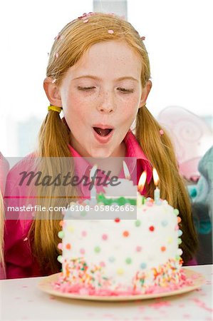 Girl blowing out candles on a birthday cake