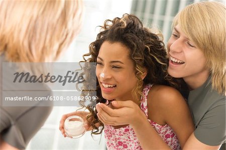 Teenage boy applying moisturizer on a girl's face