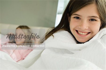 Portrait of a girl smiling with her sister talking on a mobile phone in the background