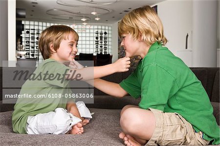 Two boys touching each other's chin and smiling