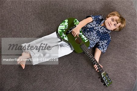 Garçon couché sur une table ronde et joue une guitare