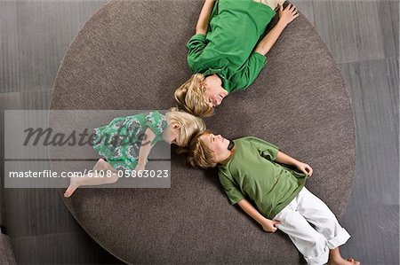 Three friends lying on a round sofa