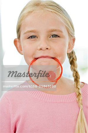 Portrait d'une jeune fille tenant un bonbon dans sa bouche