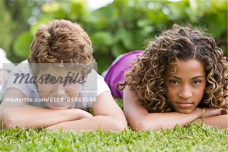 Boy lying with his sister in a garden