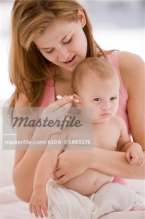 Femme oreille de sa fille avec un cotton-tige de nettoyage