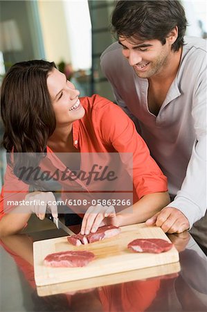 Femme, couper des tranches de viande et de sourire à un homme