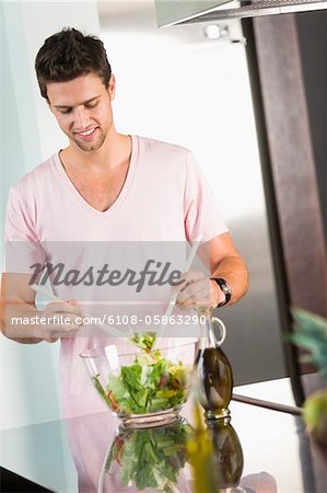 Man mixing vegetable salad in the kitchen