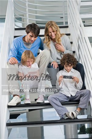 Parents assis sur les marches avec leurs enfants jouer à des jeux vidéo
