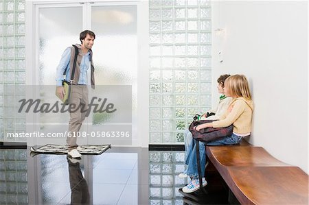 Homme qui marche vers ses enfants en attente dans un hall d'entrée