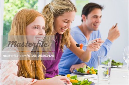 Fille avec ses parents à la table à manger