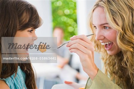 Woman feeding fruit salad to her daughter