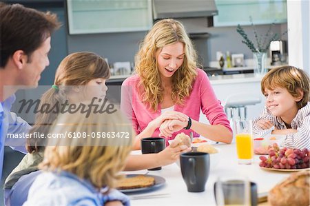 Frau, Prüfung der Zeit und dem Frühstück mit ihrer Familie