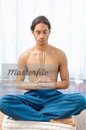 Man Yoga üben und holding Räucherstäbchen