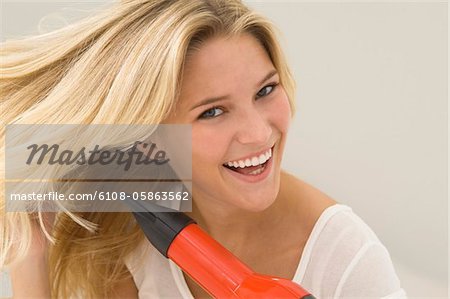 Femme séchant ses cheveux avec un séchoir à cheveux
