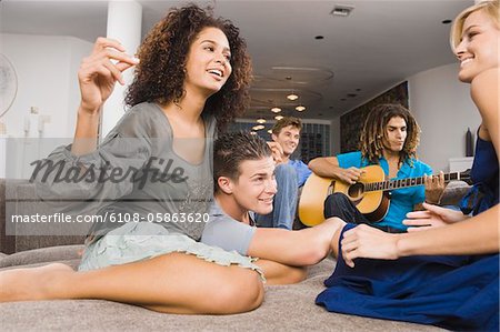 Man sitting with his friends and playing a guitar