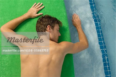 Vue d'angle élevé d'un homme se faire bronzer au bord de la piscine