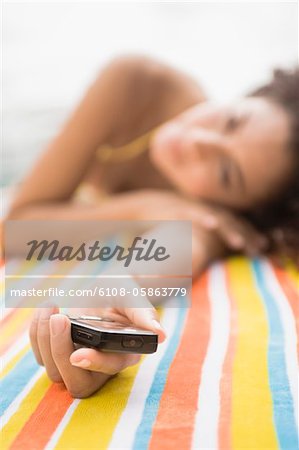 Woman lying at the poolside and holding a mobile phone