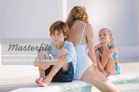 Woman with her two children sitting at the poolside