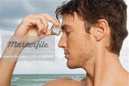 Man rubbing an ice cube on his forehead