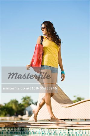 Woman walking with a bag at the poolside