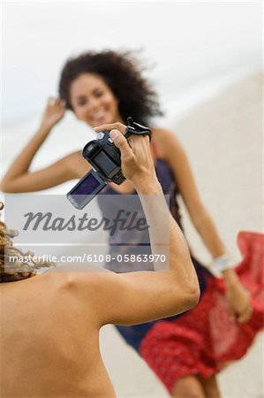 Man making a video of a woman on the beach