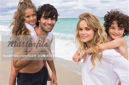 Couple giving piggyback Fahrt mit ihren Kindern am Strand