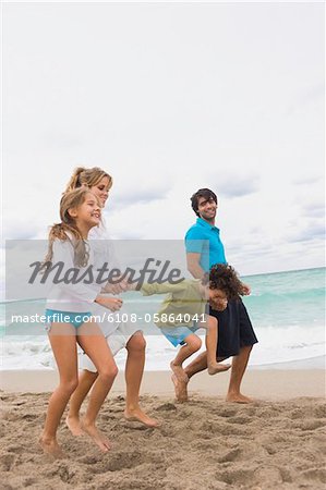 Famille en cours d'exécution sur la plage