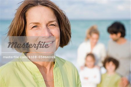 Ihre Familie hinter ihr am Strand lächelnde Frau