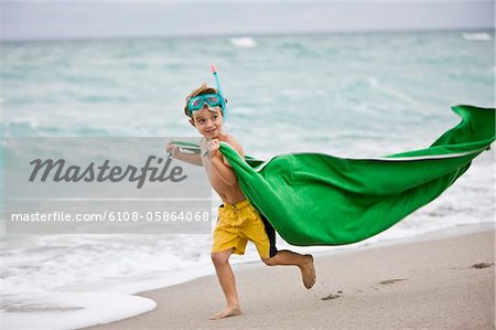 Boy wearing a scuba mask and running on the beach