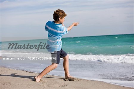 Garçon jette une pierre dans la mer