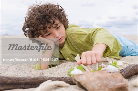 Jungen spielen mit Sand am Strand