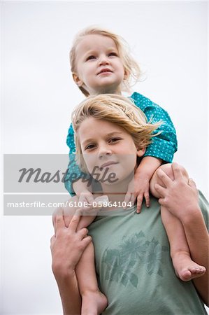 Junge mit seiner Schwester auf die Schultern am Strand