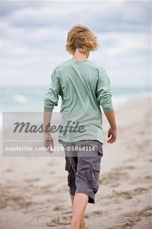 Vue arrière d'un garçon marche sur la plage