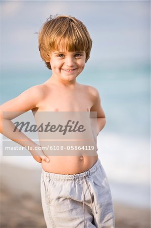 Portrait d'un garçon debout avec les bras sur les hanches et souriants