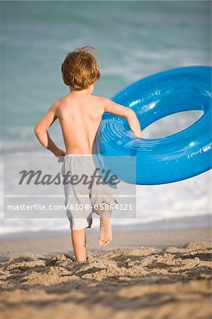 Garçon transportant un anneau gonflable sur la plage