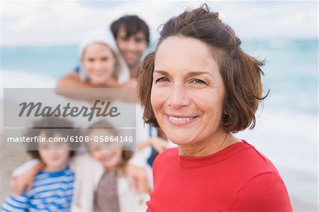 Frau lächelnd mit ihrer Familie am Strand