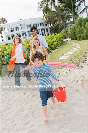 Family walking on the beach with a tourist resort in the background