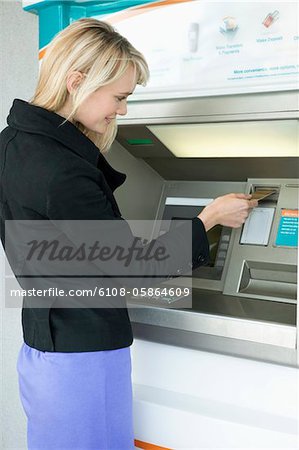 Femme, insertion d'une carte de crédit en ATM