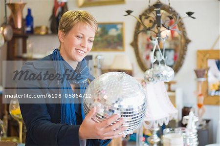 Frau hält eine Disco-Kugel in einem Geschäft
