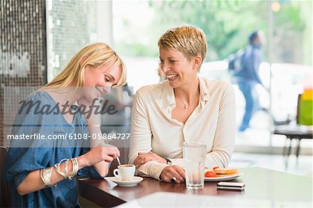 Two women sitting in a restaurant and smiling