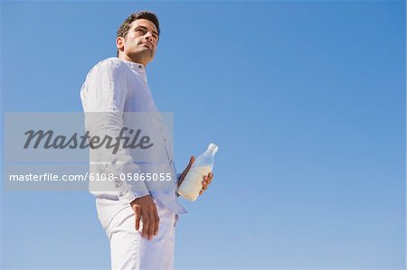 Mann, hält die MilchFlasche am Strand