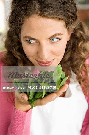 Woman smelling spinach leaves in the kitchen