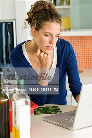 Woman reading a recipe on a laptop in the kitchen
