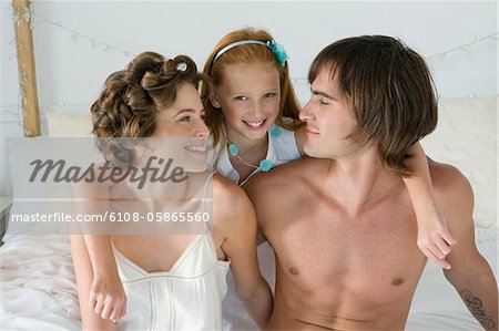 Couple souriant avec leur fille sur le lit